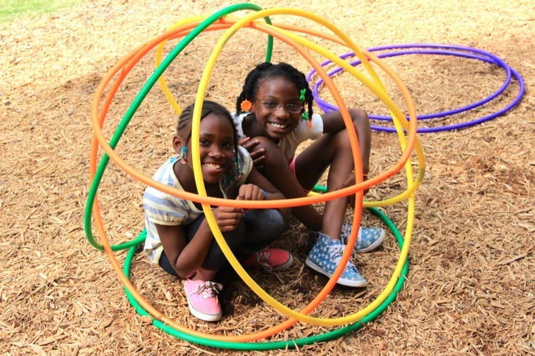 Two smiling campers playing inside a tangle of hula hoops
