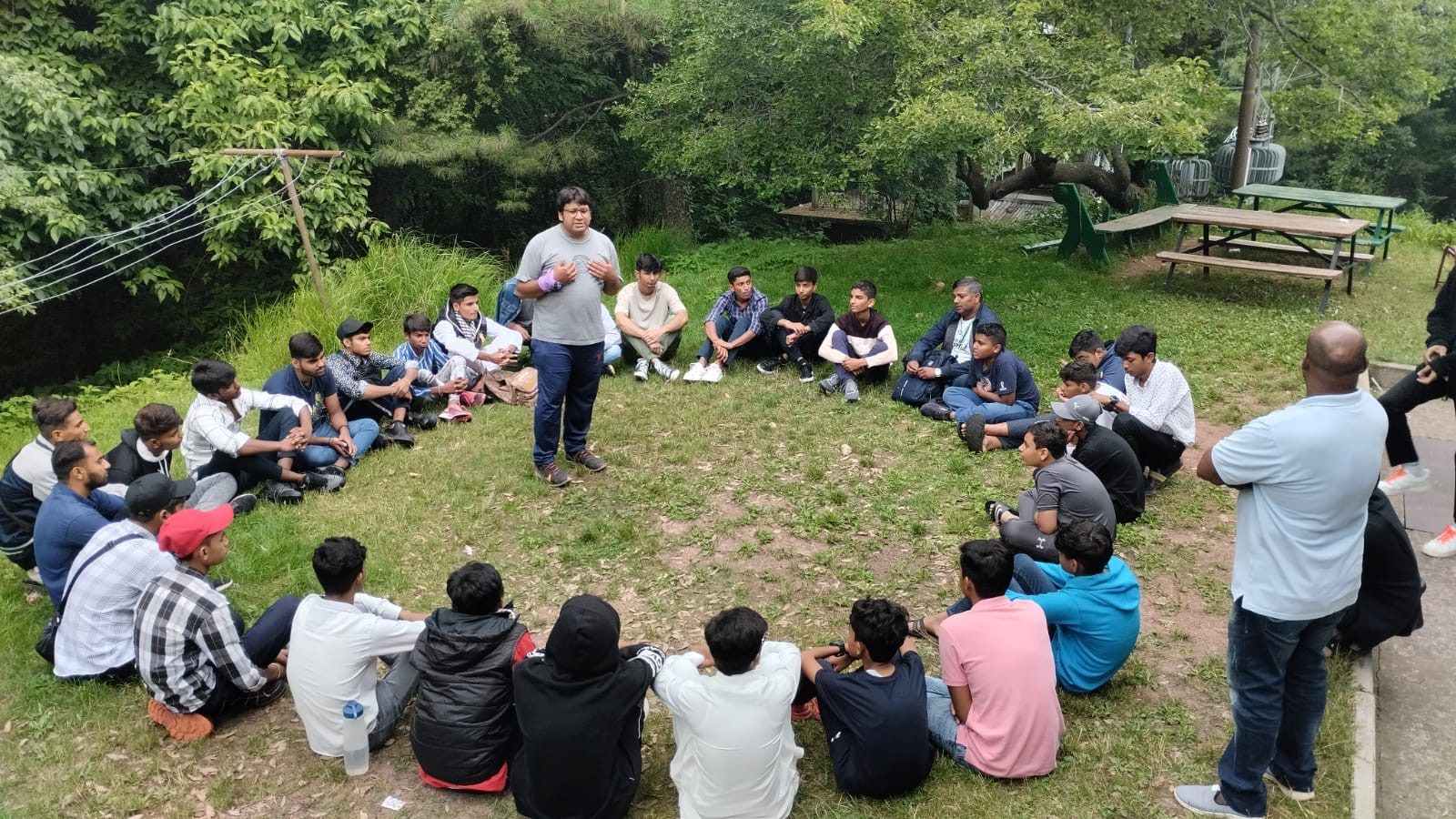 An outdoor camp Bible class seated in a circle on the grass