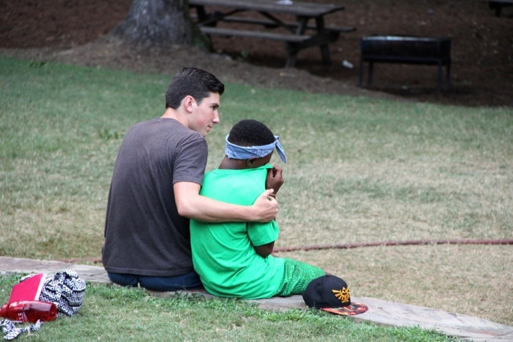 A counselor with his arm around a young camper