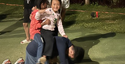 Children climbing on a counselor during a camp game