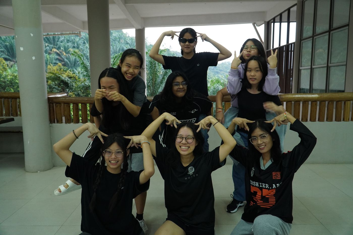 A group of girls posing with arms raised on the veranda