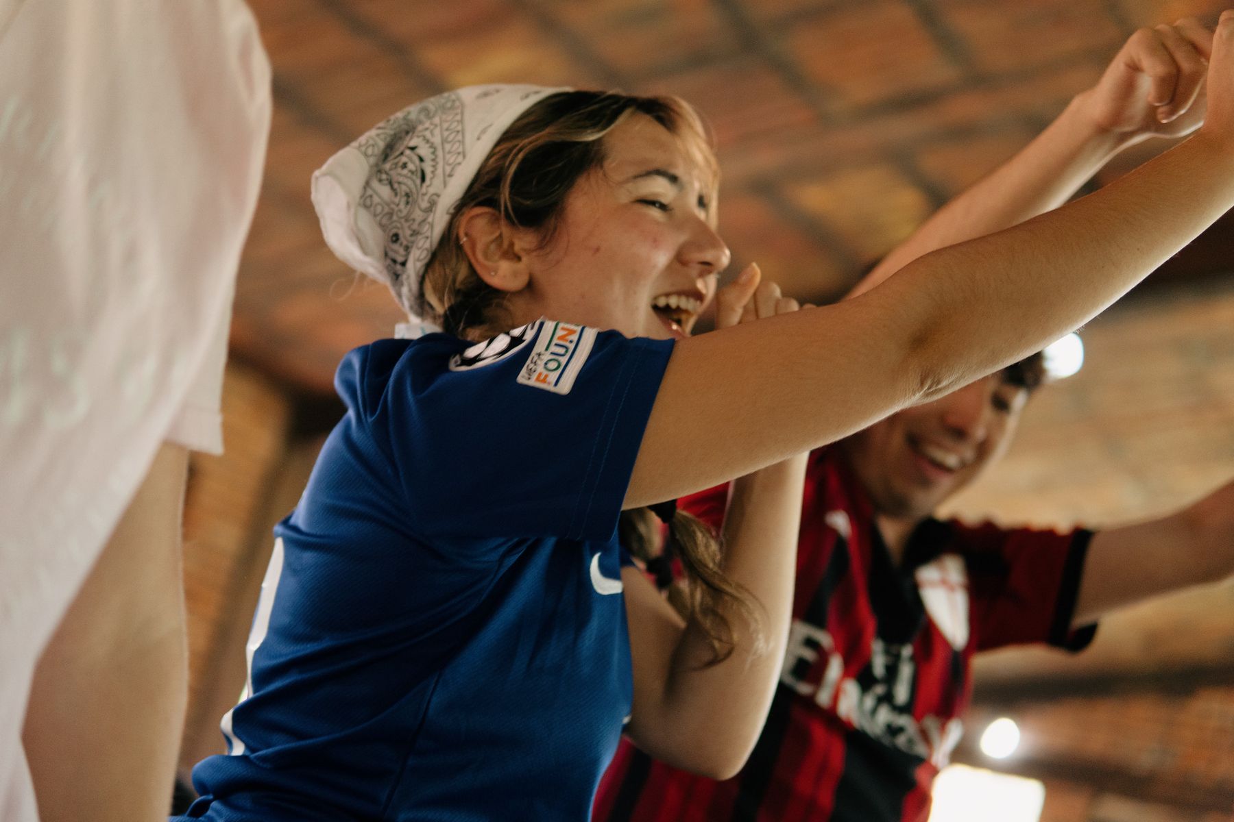 A young woman in a bandana laughing with her arms outstretched