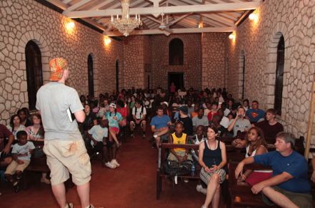 Older campers seated in a brick chapel listening to a teacher