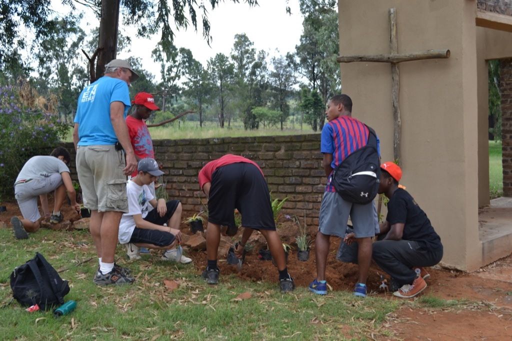 A team digging and planting together at the camp entrance