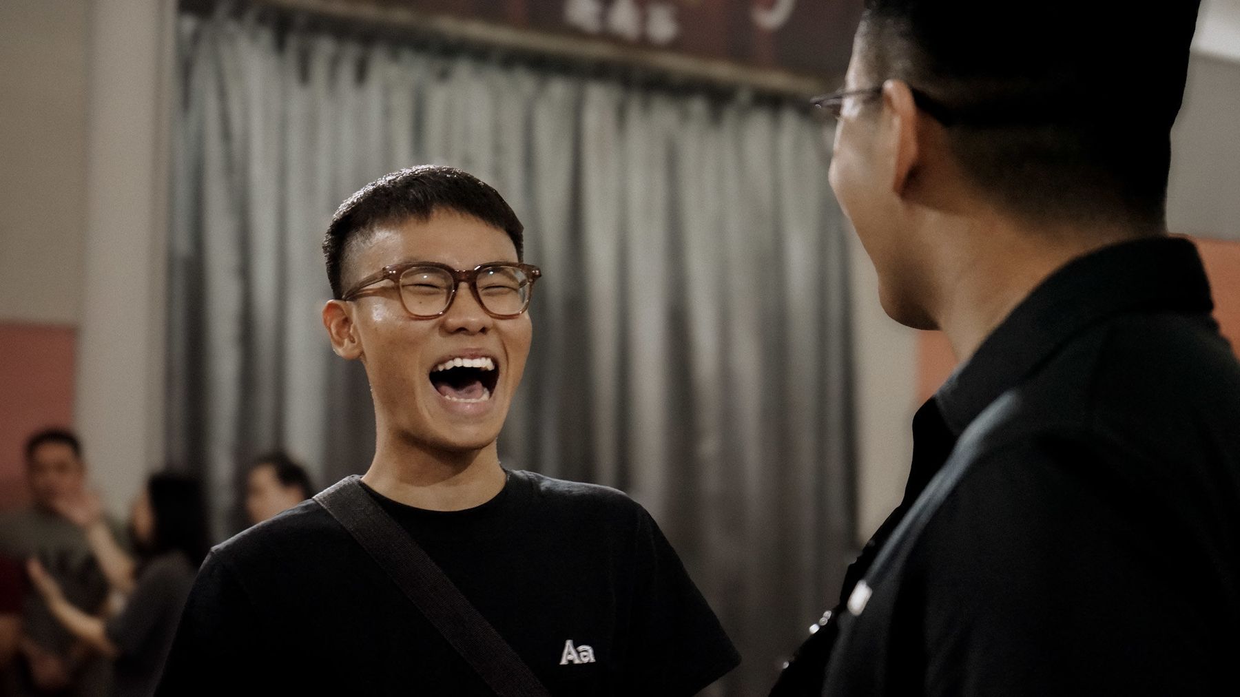 A young man in glasses laughing out loud at Swamp Camp Malaysia